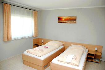 Hell eingerichtetes Zimmer mit zwei Einzelbetten, einem Nachttisch und einem Fenster im G&auml;stehaus Boardinghouse Stapf.