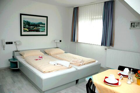 Modern eingerichtetes Schlafzimmer mit zwei Einzelbetten, Tisch und Fenster im G&auml;stehaus Boardinghouse Stapf zeigt gem&uuml;tliche Atmosph&auml;re.