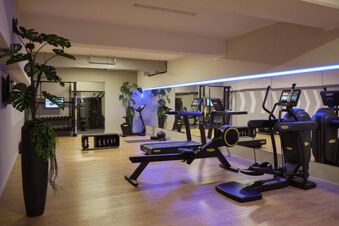 Modern ausgestatteter Fitnessraum im Leonardo Royal Hotel Mannheim mit Laufb&auml;ndern, Ruderger&auml;t, Hanteln und hellen Holzb&ouml;den.