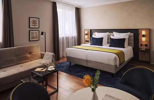 Helles und modern eingerichtetes Zimmer im Leonardo Royal Hotel Mannheim mit gro&szlig;em Bett, Sofa und stilvoller Dekoration.