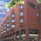 Die moderne Fassade des Leonardo Hotel Mannheim City Centre mit rotem Backstein und Fensterreihen unter blauem Himmel in Mannheim.