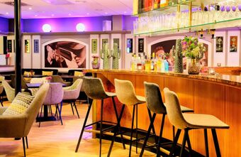 Barbereich mit Theke, Barhockern und Sitzpl&auml;tzen im stilvollen Ambiente des Leonardo Hotel Mannheim City Centre mit moderner Beleuchtung und Dekoration.