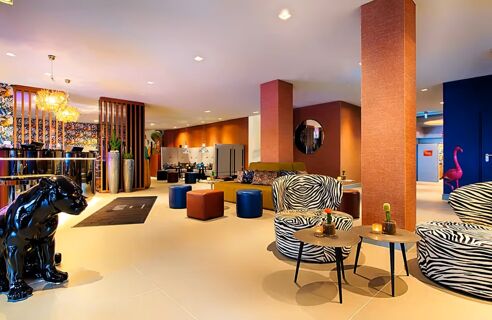 Moderne und farbenfrohe Hotellobby im NYX Hotel Mannheim mit einzigartiger Zebramuster-Sitzm&ouml;beln und verspielten Dekorationen wie einem schwarzen Panther und pinken Flamingos.