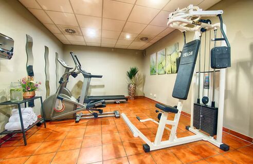 Moderner Fitnessraum mit Trainingsger&auml;ten, Handt&uuml;chern und Dekoration im Leonardo Hotel Mannheim-Ladenburg f&uuml;r G&auml;ste.