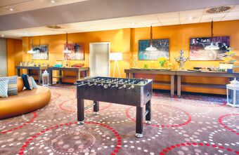 Spiel- und Loungebereich mit Kicker, dekorierten W&auml;nden und Snacks im Leonardo Hotel Mannheim-Ladenburg mit modernen Farben.