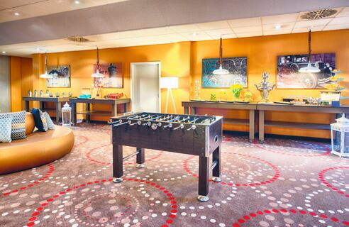 Spiel- und Loungebereich mit Kicker, dekorierten W&auml;nden und Snacks im Leonardo Hotel Mannheim-Ladenburg mit modernen Farben.
