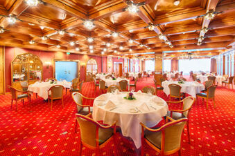 Dining room with round tables covered in white tablecloths and wooden chairs at Leonardo Hotel Heidelberg-Walldorf