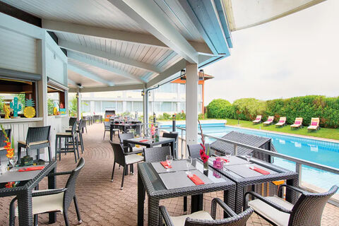 Outdoor dining area with tables, chairs, and a pool at Leonardo Hotel Heidelberg-Walldorf under a white roof canopy