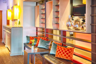 Modern lounge area with black cushioned benches orange and teal pillows and decorative vases at Leonardo Hotel Heidelberg-Walldorf