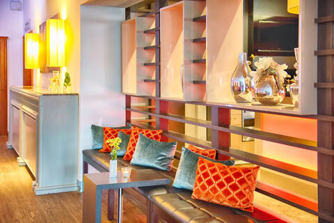 Modern lounge area with black cushioned benches orange and teal pillows and decorative vases at Leonardo Hotel Heidelberg-Walldorf