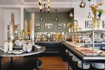 Buffet breakfast area with cereals, milk, juices, cold cuts, and bowls at Leonardo Hotel Heidelberg City Center
