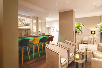 Modern hotel bar area with colorful stools, beige chairs, glass tables, and pendant lighting at Leonardo Hotel Heidelberg City Center