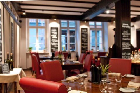 Dining area with red leather chairs, wooden tables set with wine bottles, glasses, and menus at Gasthaus Backmulde - Hotel
