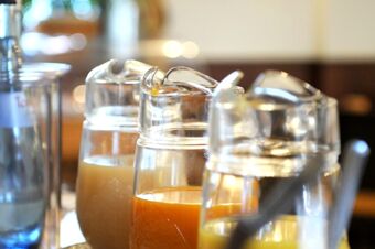 Tiga kafetaria dengan jus yang berbeda di atas meja di Gasthaus Backmulde - Hotel, ideal untuk sarapan prasmanan.