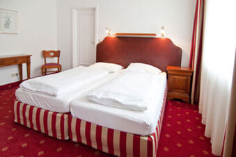 Kamar tidur yang cerah dengan dua tempat tidur single dan karpet merah di Gasthaus Backmulde - Hotel, dilengkapi dengan perabotan yang sederhana dan nyaman.