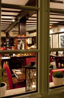 View through a window into a dining area with red chairs, wooden beams, framed pictures, and a decorative cabinet at Gasthaus Backmulde - Hotel