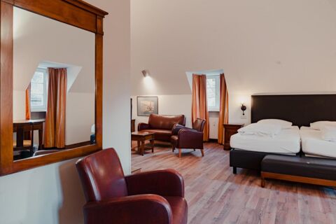 Room at Gasthaus Backmulde - Hotel with a large mirror, two red leather chairs, a bed, side tables, and two windows with curtains