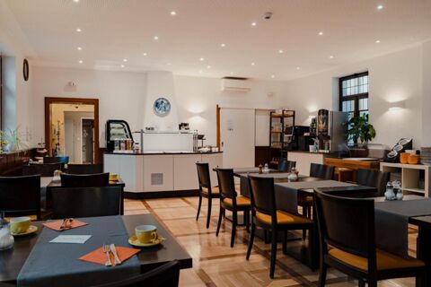 Dining area with black chairs and tables set with yellow cups and orange napkins at Gasthaus Backmulde - Hotel