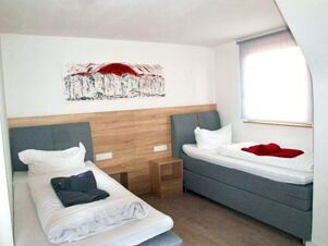 Two single beds with white linens and folded towels in a brightly lit room at Gasthof zur Sonne