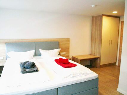 A clean hotel room at Gasthof zur Sonne with two single beds side by side, wooden furniture, and folded towels on the bed