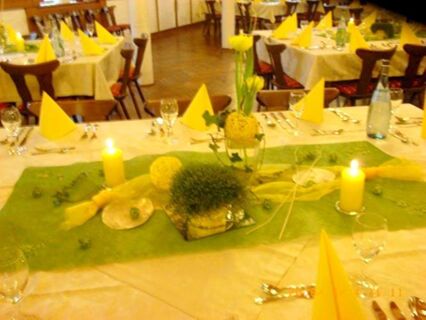 Mesas festivas com guardanapos amarelos e decora&ccedil;&otilde;es num restaurante do Gasthof zur Sonne com luz quente.