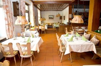 Svetla in prijetna restavracija v hotelu Krone s tradicionalnim lesenim pohi&scaron;tvom, obloženimi mizami in okrasnimi svetilkami.