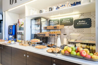 Breakfast buffet with pastries, fruits, yogurts, milk, cold cuts, and coffee machines at B&B Hotel Ferrara
