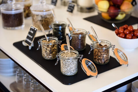 Glass jars filled with seeds, nuts, and dried fruits with spoons on a black tray at B&B HOTEL Ischia San Nicola