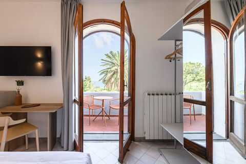 B&B HOTEL Ischia San Nicola room with open wooden balcony doors showing outdoor table and chairs under clear sky