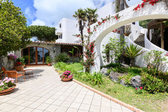 Outdoor patio area with tiled floor, seating, potted plants and green garden at B&B HOTEL Ischia San Nicola