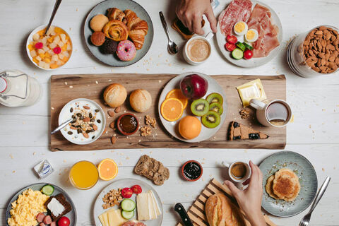 Breakfast spread with fruits, pastries, bread, nuts, cold cuts, coffee, and juice on a white table at B&B HOTEL Ischia San Nicola