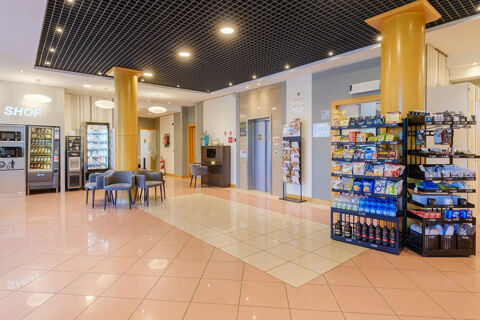 Lobby area of B&B Hotel Ravenna with snack shelves, vending machines, seating chairs, tiled floor, and elevators visible