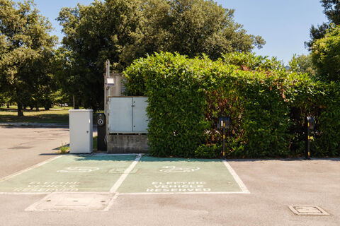 Two electric vehicle reserved parking spaces with charging stations next to green bushes at B&B Hotel Ravenna