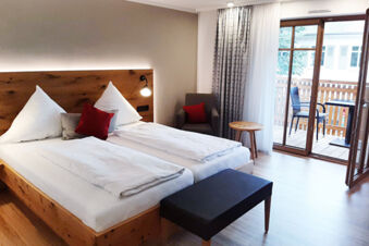 Svetl&aacute; a modern&aacute; hotelov&aacute; izba s dvoma posteľami, balk&oacute;nom a priestorom na posedenie v hoteli Gasthaus Zur Linde Diersburg.