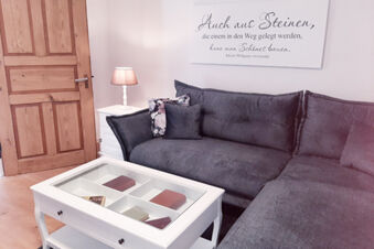 Gray couch with floral pillows next to a white coffee table and lamp in a room at Hotel Gasthaus Zur Linde Diersburg