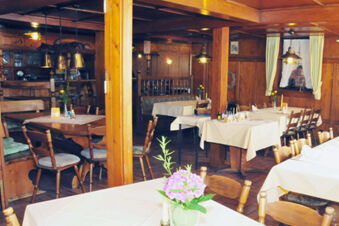 Rustik&aacute;lna jed&aacute;leň s dreven&yacute;m n&aacute;bytkom a prestret&yacute;mi stolmi v hoteli Gasthaus Zur Linde Diersburg s pr&iacute;jemnou atmosf&eacute;rou.