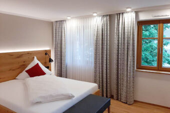 Hotel Gasthaus Zur Linde Diersburg room with a bed featuring white linens, red pillow, wooden headboard, and window with curtains