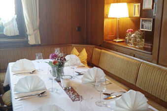 &Uacute;tuln&yacute; jed&aacute;lensk&yacute; st&ocirc;l s bielymi obr&uacute;skami a kvetinovou v&yacute;zdobou v re&scaron;taur&aacute;cii hotela Gasthaus Zur Linde Diersburg.