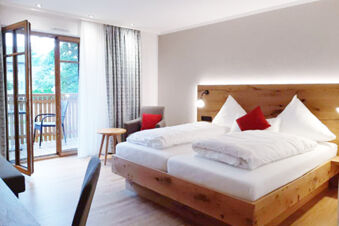 Hotel Gasthaus Zur Linde Diersburg room with wooden bed frame, white linens, armchair, side table and balcony door open to outside