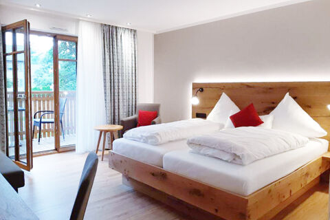 Hotel Gasthaus Zur Linde Diersburg room with wooden bed frame, white linens, armchair, side table and balcony door open to outside