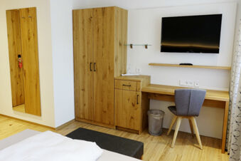 Moderne zariaden&aacute; hotelov&aacute; izba s drevenou skriňou, p&iacute;sac&iacute;m stolom, TV a poseden&iacute;m v hoteli Gasthaus Zur Linde Diersburg.