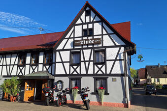 A traditional black and white half-timbered building with a red roof and three motorcycles parked outside Hotel Gasthaus Zur Linde Diersburg