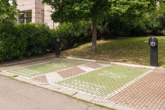 Two green electric vehicle charging parking spots with charging stations beside a building near greenery at B&B Hotel Faenza