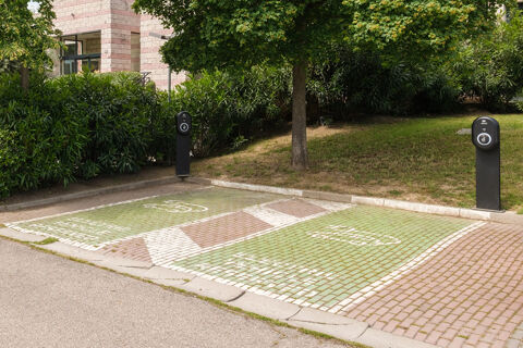 Two green electric vehicle charging parking spots with charging stations beside a building near greenery at B&B Hotel Faenza