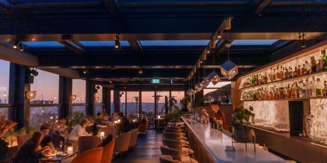 Interior view of a dimly lit restaurant and bar area at InterContinental Rome Ambasciatori Palace with patrons seated at tables and stools