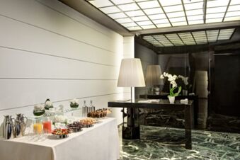 A buffet table with drinks and desserts next to a black glossy table with a lamp and white orchid at Grand Hotel Palace