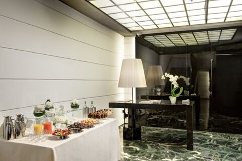A buffet table with drinks and desserts next to a black glossy table with a lamp and white orchid at Grand Hotel Palace