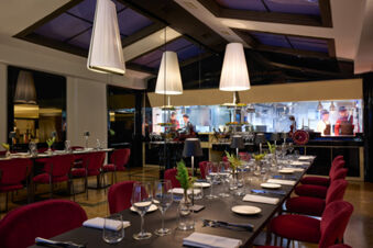 Dining area with tables set with wine glasses, plates, cutlery, and red chairs at Grand Hotel Palace