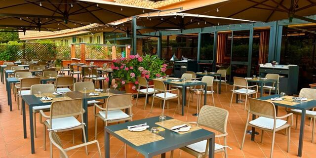 Outdoor dining area with multiple tables and chairs, place settings, and flowers at Crowne Plaza Rome -St. Peter's