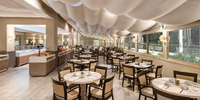 Dining area at Crowne Plaza Rome -St. Peter's with tables and chairs neatly arranged and large windows providing outdoor views